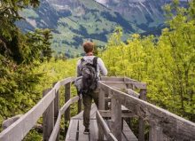 boy with backpack on walking with green views