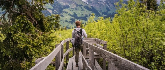 boy with backpack on walking with green views