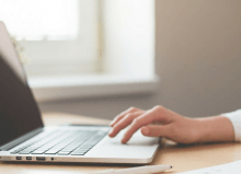 woman typing on laptop at her desk with blank screen