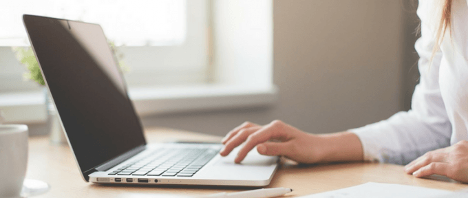 woman typing on laptop at her desk with blank screen