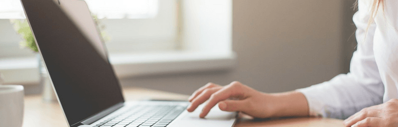 woman typing on laptop at her desk with blank screen