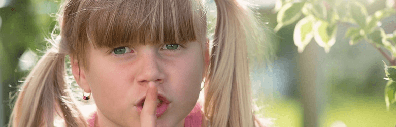 little girl with finger on her lips in quiet environment