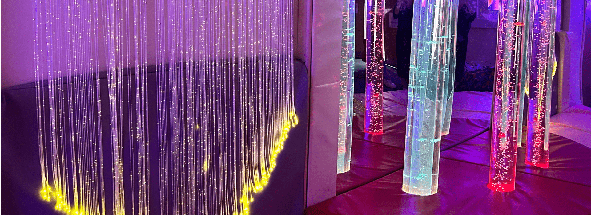 Multisensory room featuring illuminated bubble tubes and hanging fiber optic strands, glowing in calming colors like purple, yellow, and red, designed to provide a soothing environment for sensory stimulation and relaxation.